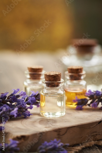 Transparent bottles of essential oil with fresh lavender flowers