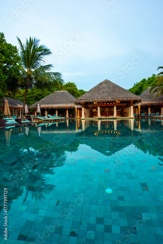 Tranquil closeup calm sea water waves with palm trees. Cabins near pool. Tropical island beach landscape exotic shore coast. Summer vacation, holiday amazing nature. Relax paradise, Maldives.