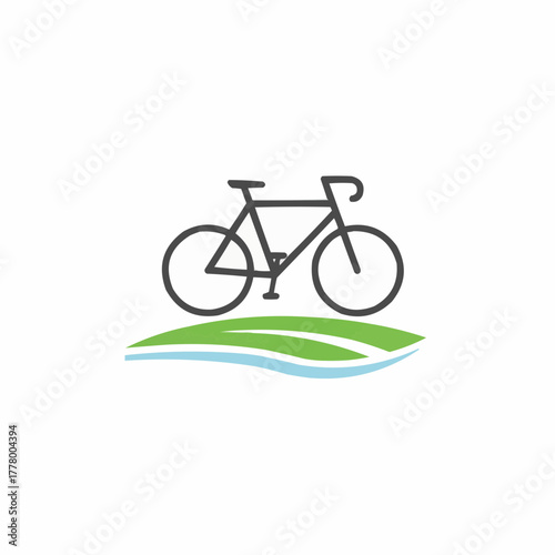 Silhouette of a bicycle on green grass with a blue water stream below it