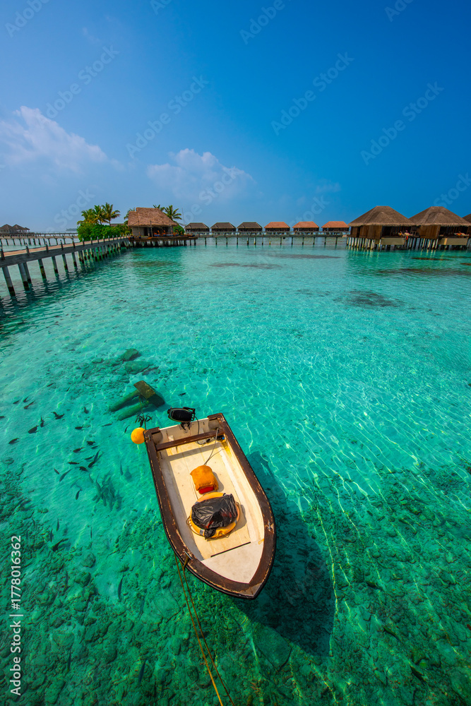 Fototapeta premium Tranquil closeup calm sea water waves with palm trees. Boat and bungalows background. Tropical island beach landscape exotic shore coast. Summer vacation, holiday amazing nature, Maldives.