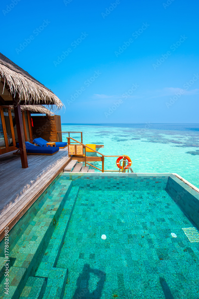 Fototapeta premium Tranquil closeup calm sea water waves with palm trees. Cabin with pool. Tropical island beach landscape exotic shore coast. Summer vacation, holiday amazing nature. Relax paradise, Maldives.