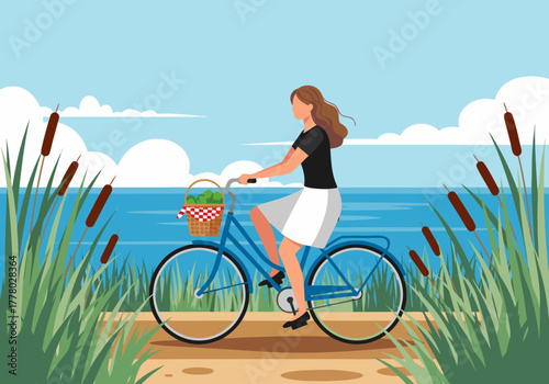 A young woman enjoys cycling by the lakeside with cattails under a cloudy sky