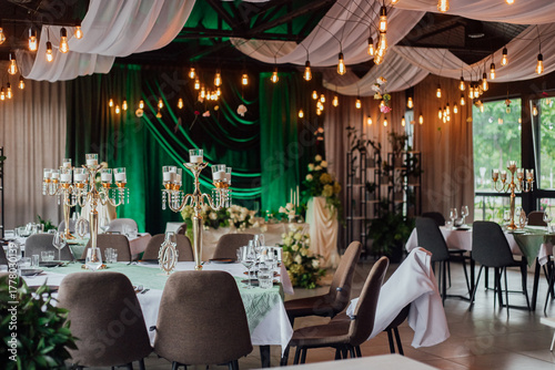 Elegant indoor wedding reception with green drapes and candlelit decor