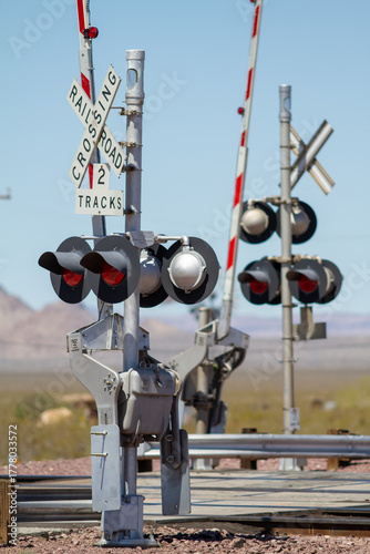 at grade railroad crossing that just along a highway in rural southwest desert of the united state where cargo trains carry goods inexpensively inland from coastal ports