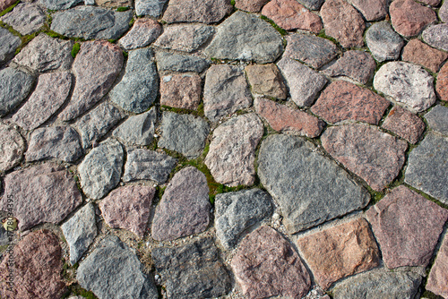 Fragment of a road made of granite stones. Paving stones made of granite stones on an old road. Stone background.