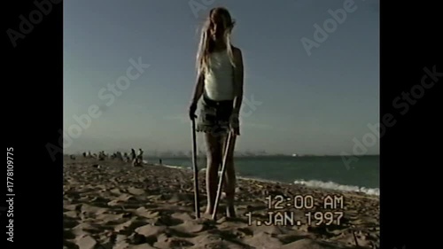 Girl standing on sandy beach in vintage VHS 1997 home video style with analog tape look and nostalgic feeling