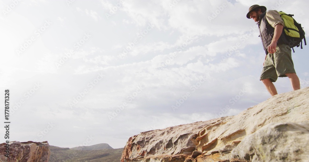 Naklejka premium Hiker standing on rocky outcrop viewing canyon, with backpack, sunhat and hiking boots, copy space