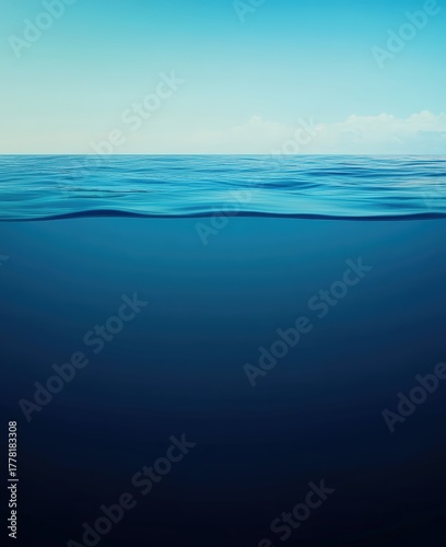 Fototapeta Naklejka Na Ścianę i Meble -  Calm blue sea split view, clear sky above, tranquil underwater gradient below showing serene ocean depth and glassy horizon reflection
