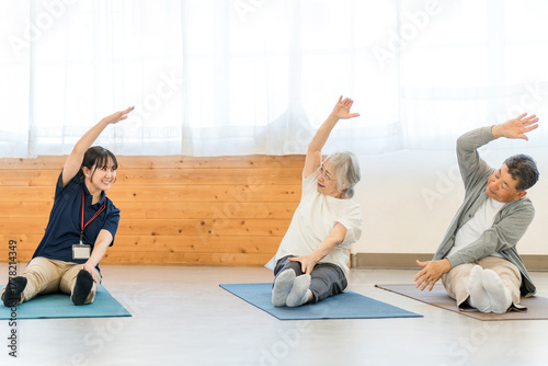 Nursing home, rehabilitation at welfare center, seniors stretching, elderly men and women with occupational therapist, caregiver, trainer
