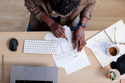 Person reviews invoices at desk with laptop and coffee.