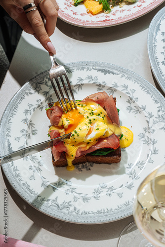 Cutting into eggs benedict on toast with runny yolk