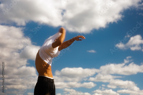 A Man Takes Off His T-Shirt Outdoors In Summer
