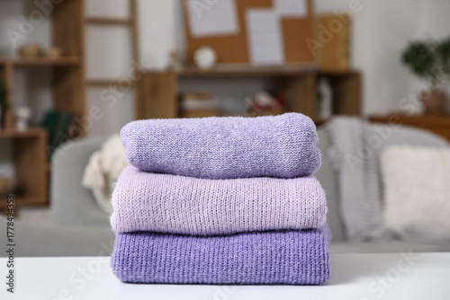 Stack of stylish winter purple sweaters on table in living room