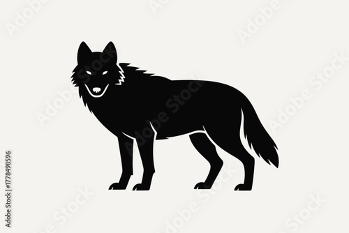 Silhouette of a fierce black wolf standing alert on a light background