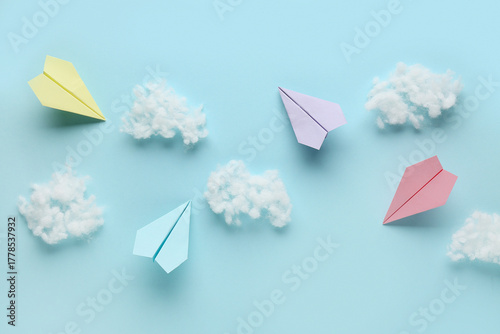 Colorful paper planes with cotton wool clouds on blue background