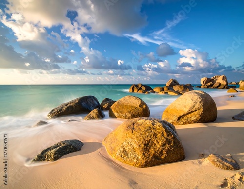 Sandy beach with large, smooth rocks under a cloudy sky