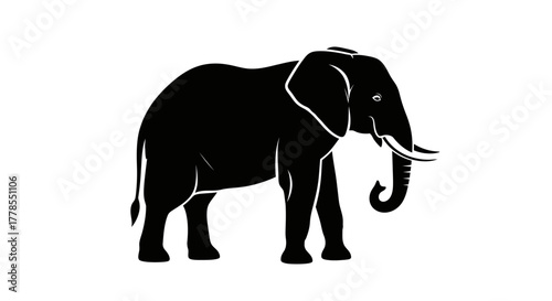 Silhouette of an elephant standing, with its trunk curled and tusks visible, against a white background.