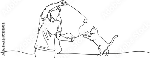 A person in silhouette playfully swings a string toy engaging a leaping cat in an energetic game playing animal pet movement