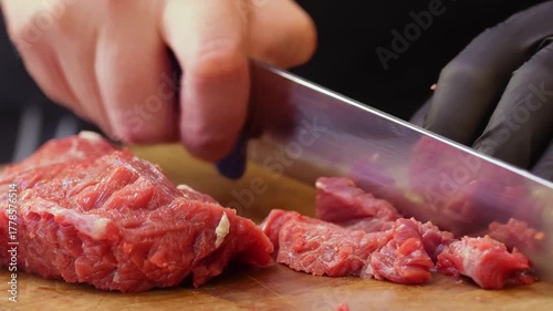 Hands of skilled butcher slicing red meat with precision in a professional environment