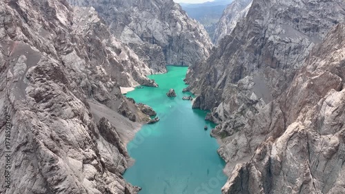 High angle view of Kel-Suu Lake, a winding alpine lake known for its vibrant turquoise water and dramatic sheer cliffs that form a narrow canyon