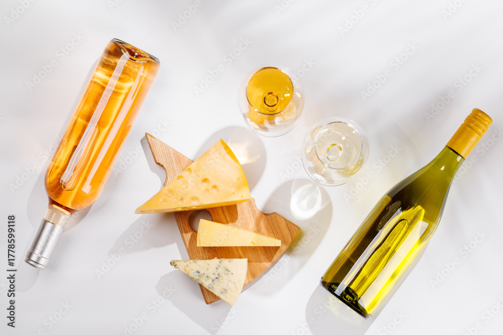 Fototapeta premium Assorted cheeses and wine bottles on white background