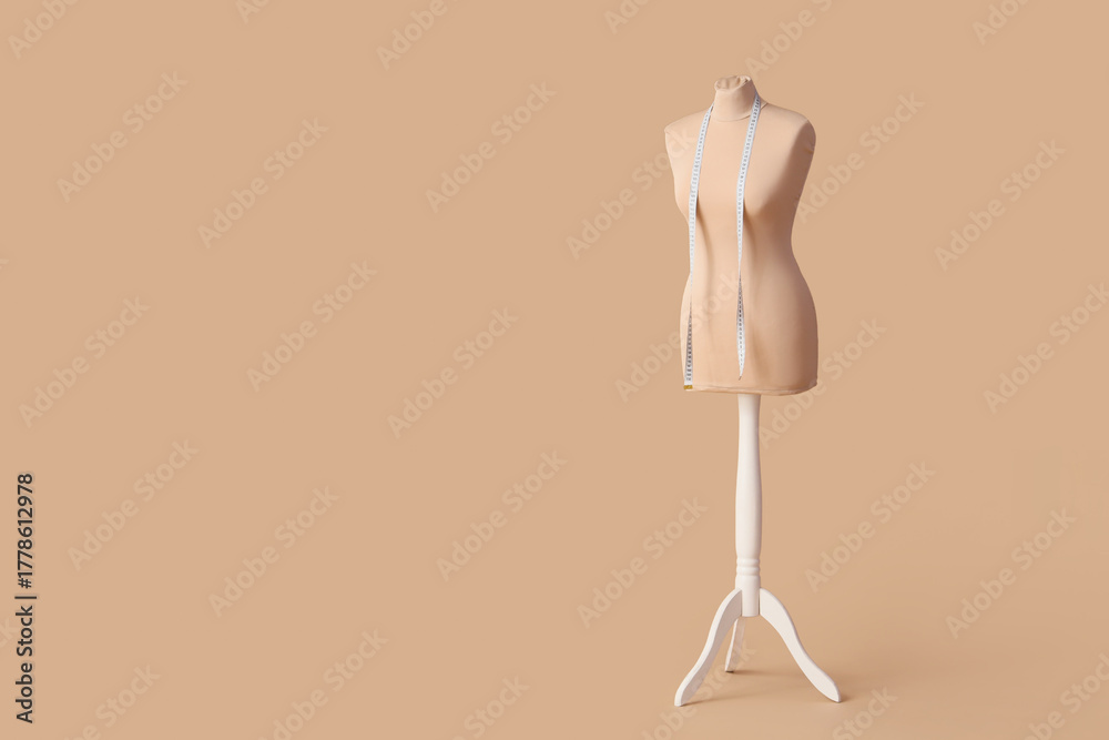 Fototapeta premium Mannequin for tailor with measuring tape on beige background