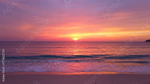 A vivid beach scene showcases a fiery sunset over the calm ocean, with footprints on the shore