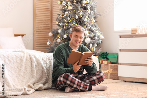 Young man reading book in b...