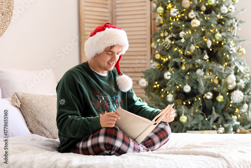 Young man in Santa hat read...