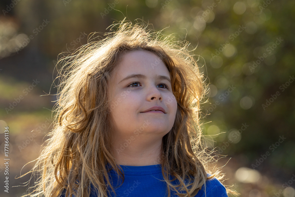 Fototapeta premium Carefree kid in a meadow. Child imagining. Outdoor portrait of a dreamer kid. Freedom and innocence in childhood. Cute kid outdoor portrait. Dreamy kids face. Carefree childhood. Dreamy child.