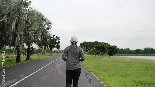 Asian woman jogging in slow motion at sunrise in a peaceful park. Morning exercise boosts circulation, energy, and wellness. A perfect start to healthy living.