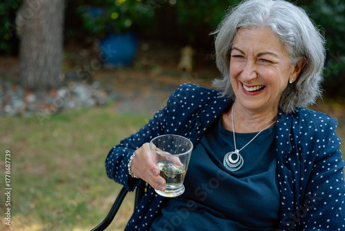 Smiling senior woman outdoors with a glass of wine