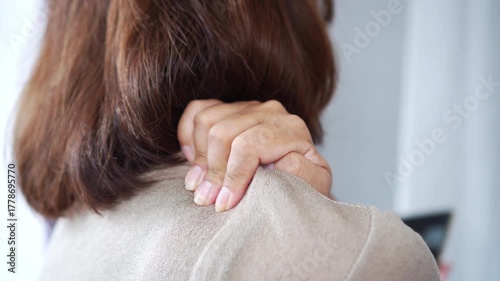 Woman massaging her neck and shoulder in pain after using a mobile phone too long with bad posture. Concept of tech neck, smartphone addiction, muscle strain, and poor posture health issues