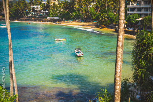 Turquoise lagoon with palm trees, boats and beach resorts in Sri Lanka