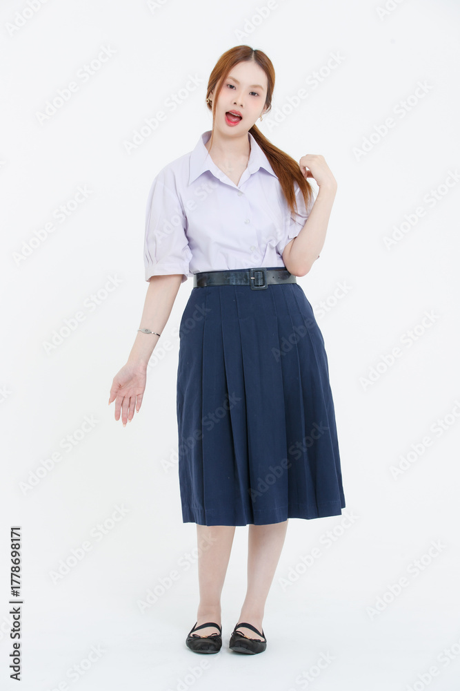 Fototapeta premium Studio portrait of asian cheerful beautiful happy young woman wearing white blouse, navy pleated skirt, black flats posing on white background, student high school uniform, education lifestyle concept