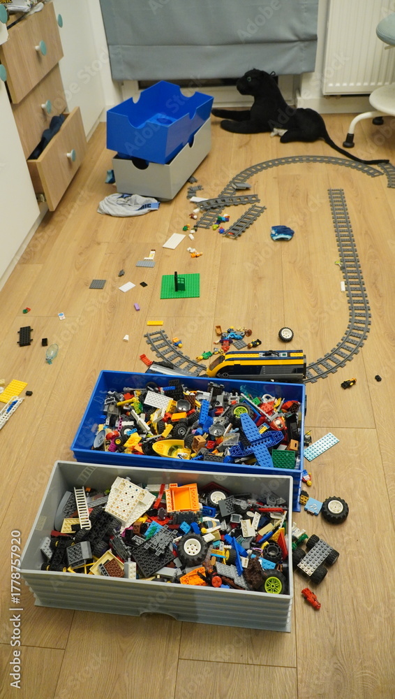Naklejka premium A messy room with scattered LEGO bricks, building materials, and a cat, representing childhood and play