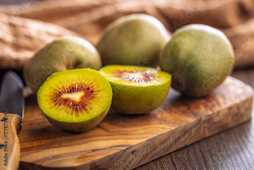 Red kiwi fruit on cutting board on wooden table.