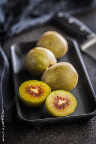 Red kiwi fruit on plate on black table.