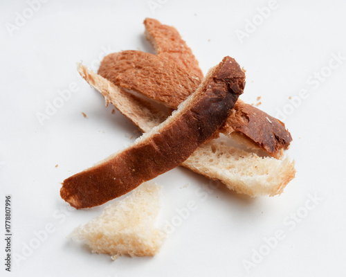 Sad pile of leftover burnt bread crust on white background symbol of food waste and overcooked breakfast toast showing dry discarded brown and black snack
