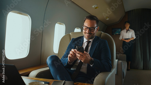 Fotografia Business executive in a tailored suit and glasses smiles while using a smartphon