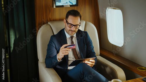 Obraz na płótnie Man in a business suit using a credit card and digital tablet for online shoppin