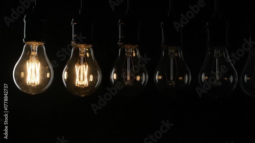 A lit lightbulb shines amongst others unlit, creating contrast and focus against a dark backdrop
