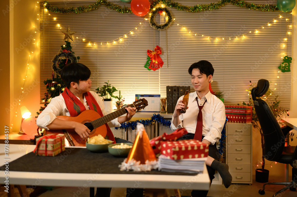 Fototapeta premium Two coworkers unwind after hours with music and drinks, surrounded by festive Christmas decor and twinkling lights