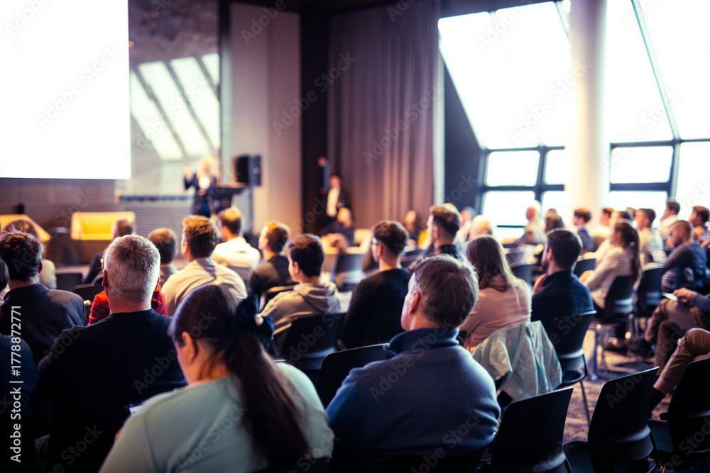 Obraz premium Speaker giving a talk in conference hall at business event. Rear view of unrecognizable people in audience at the conference hall. Business and entrepreneurship concept