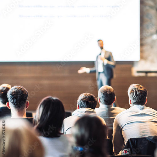 Speaker giving a talk in conference hall at business event. Rear view of unrecognizable people in audience at the conference hall. Business and entrepreneurship concept