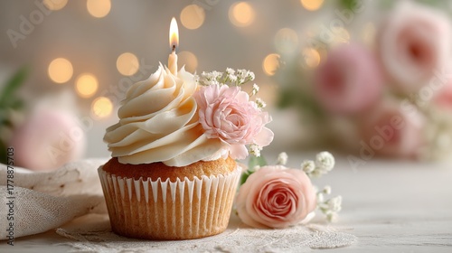 Elegant cupcake with floral decoration and candle on a wooden table