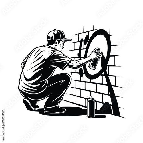 Urban artist in baseball cap crouches to spray paint a large circle on a brick wall with a can