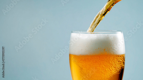 Wallpaper Mural Cold golden beer being poured into a glass with thick foam head against a light blue background Torontodigital.ca