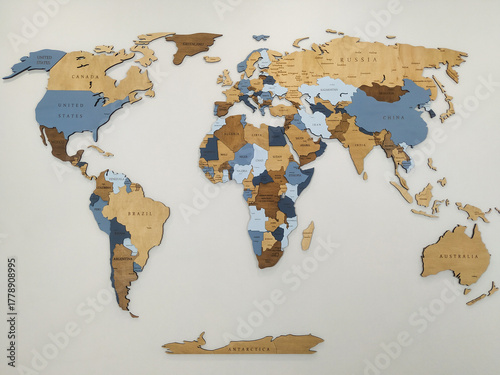 A wooden world map on a white wall. The map features various shades of blue and brown, highlighting different countries and regions