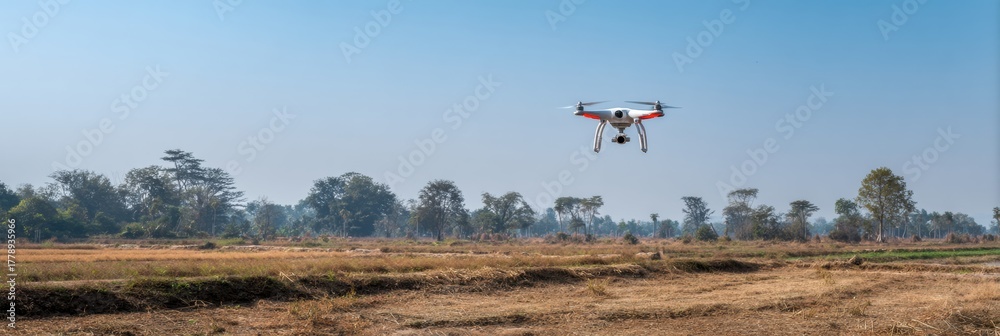 Fototapeta premium Drone Flying Over a Vast Field in a Clear Blue Sky During Daylight Hours